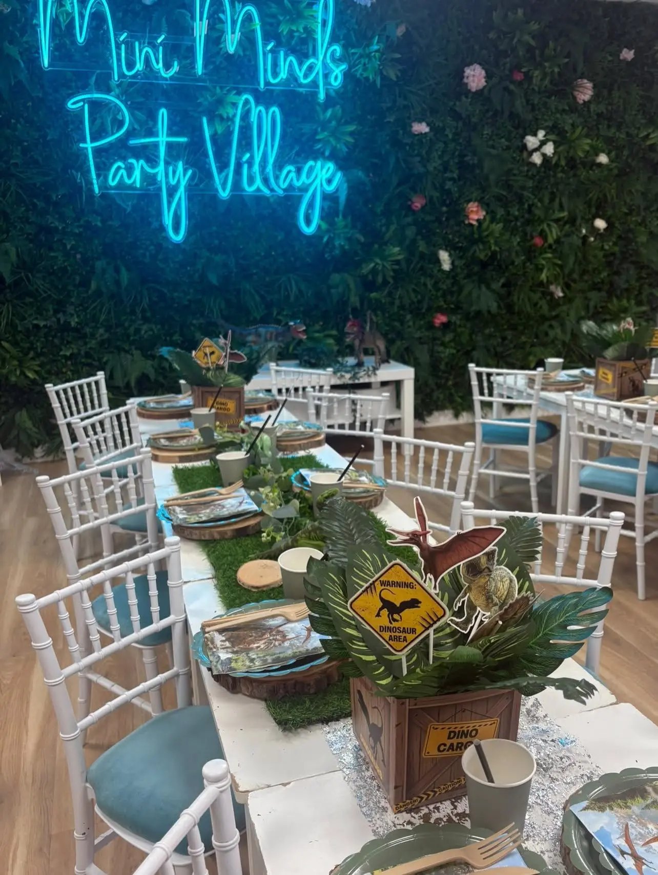 The foliage wall in the Mini Minds party room with a glowing Mini Minds sign above a decorated party table